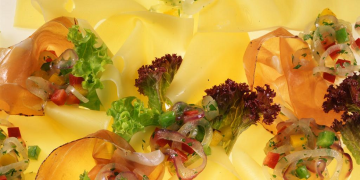 Nahaufnahme Käse-Carpaccio mitSalat, Paprikastückchen und Zwiebeln.
