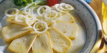 Schale mit mehreren Scheiben Limburger, dekoriert mit Zwiebelringen und Radieschen