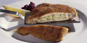 Ein angeschnittenes, mit Allgäuer Bergkäse gefülltes Schweinehalssteak